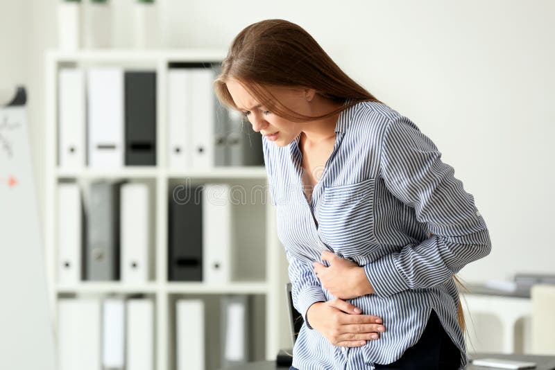 Young woman suffering from abdominal pain in office