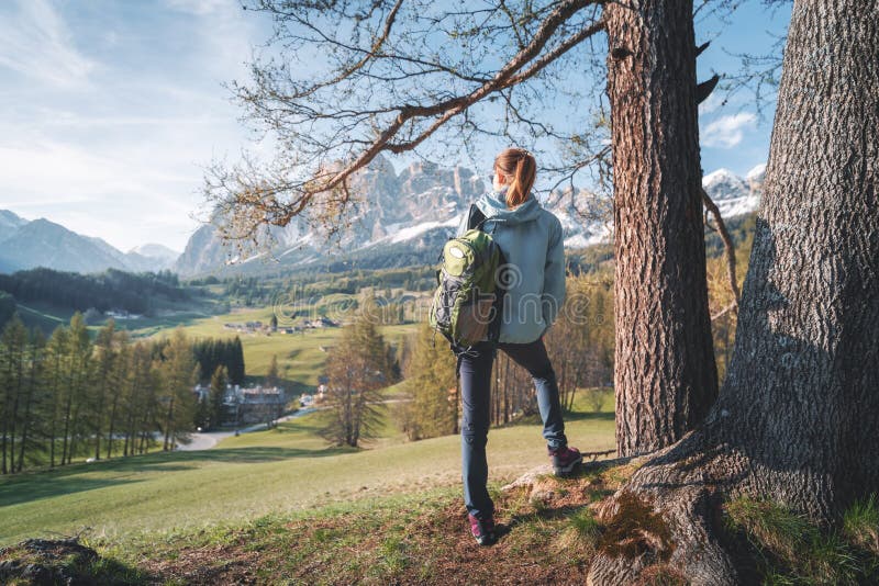 Bellissimo giovane donna occhiali da sole un blu giacca è un piedi sul collina un albero sul tramonto.