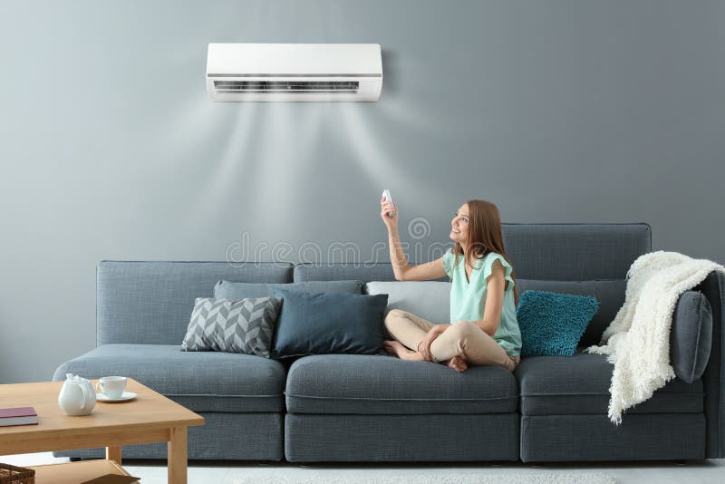 Young woman switching on air conditioner royalty free stock photography Young woman switching on air conditioner royalty free stock photography
