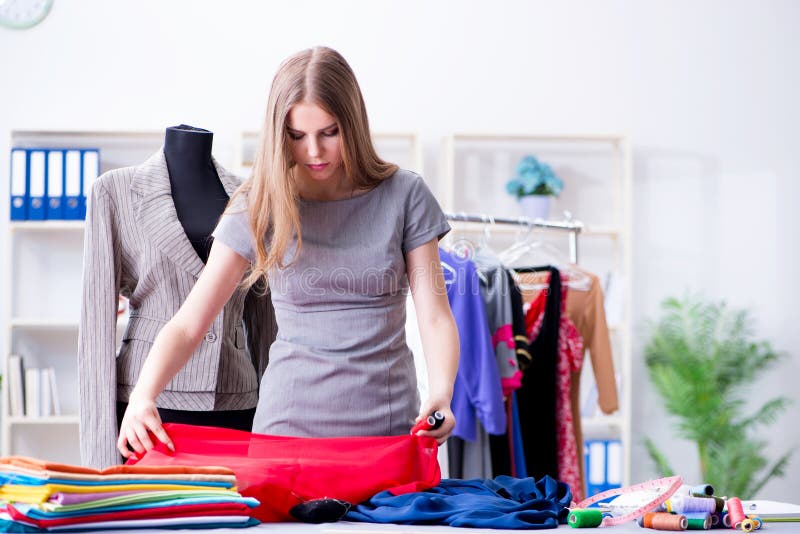 The young woman tailor working in workshop on new dress