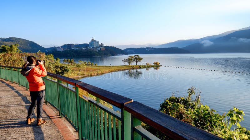 A young woman takes a photo of a beautiful natural scenery at Sun Moon Lake, Taiwan royalty free stock images A young woman takes a photo of a beautiful natural scenery at Sun Moon Lake, Taiwan royalty free stock images