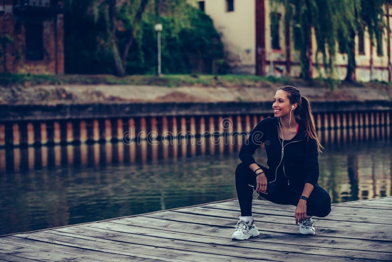 Young Woman Taking Break After Jogging By The River