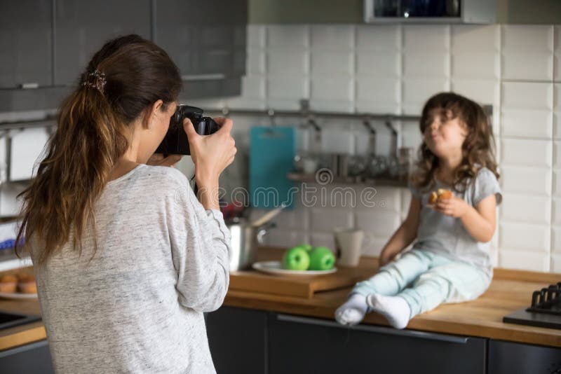 Young woman taking photo cute little girl in kitchen royalty free stock photo Young woman taking photo cute little girl in kitchen royalty free stock photo