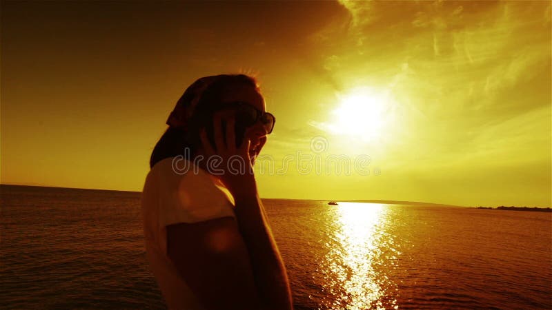 Young woman talking phone in sunset or sunrise