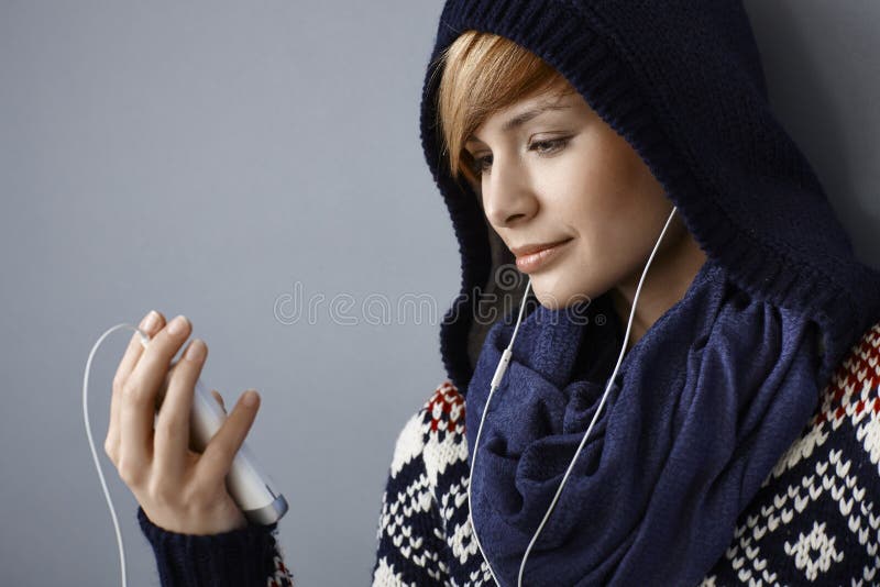 Young woman in hood talking on phone using earbuds. Young woman in hood talking on phone using earbuds