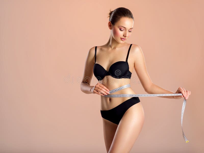 Young woman with tape and a beautiful, healthy body. Sexy woman measuring her perfect body