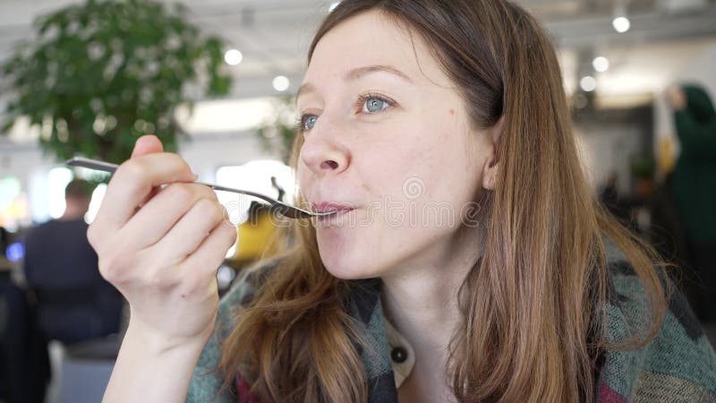 Young woman tastes food and contentedly smiles at camera