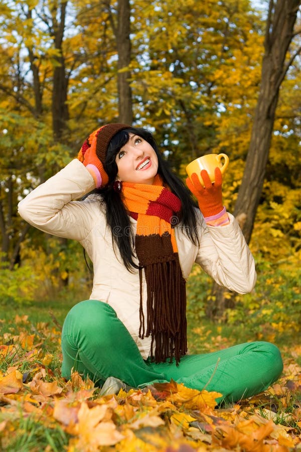 Young woman with tea cup in the autumn park