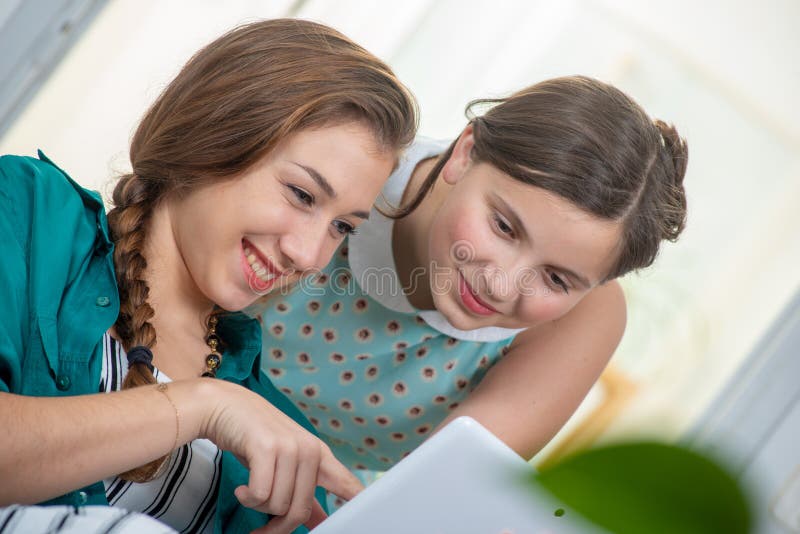 Young woman and teen girl using tablet computer at home royalty free stock photos Young woman and teen girl using tablet computer at home royalty free stock photos