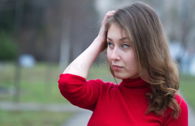 Portrait of an attractive beautiful pretty cute young caucasian successful cheerful thinking woman (girl, female, person, model) in red sweater against blurred background. Portrait of an attractive beautiful pretty cute young caucasian successful cheerful thinking woman (girl, female, person, model) in red sweater against blurred background.