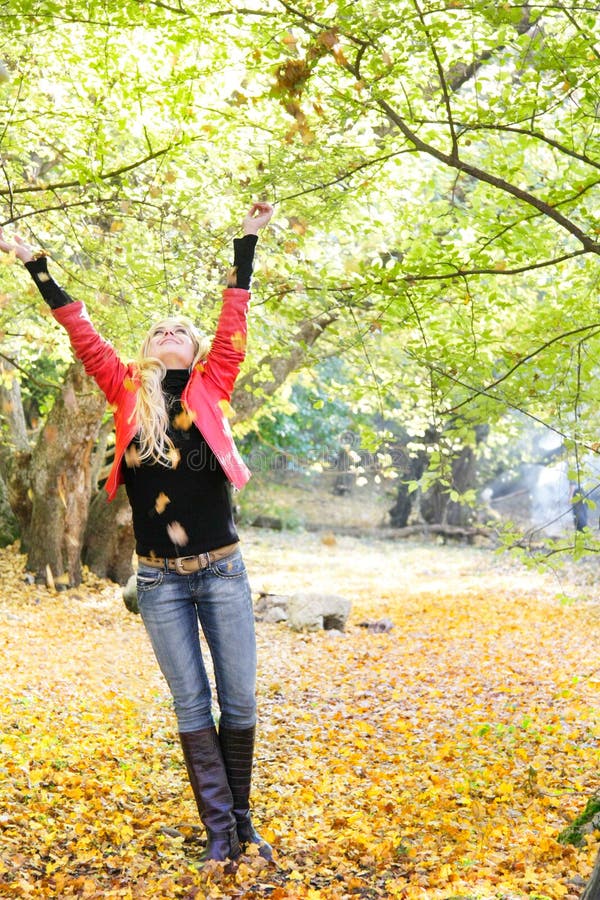 Young woman throwing leaves in park