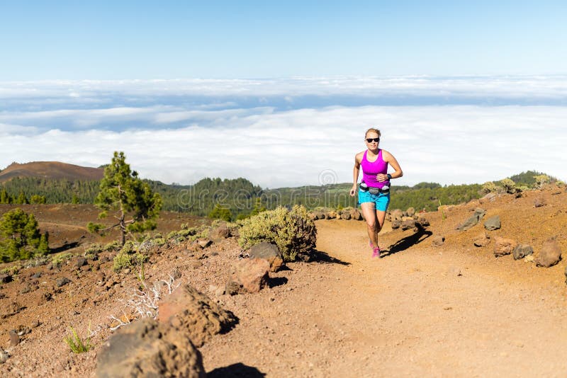 Young woman trail running in mountains on sunny summer day. Beauty female runner jogging and exercising outdoors in nature, rocky trail footpath on La Palma, Canary Islands