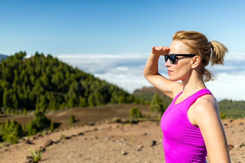 Young woman running in mountains on sunny summer day looking at view. Beauty female runner jogging and exercising outdoors in nature, rocky trail footpath on La Palma, Canary Islands. Young woman running in mountains on sunny summer day looking at view. Beauty female runner jogging and exercising outdoors in nature, rocky trail footpath on La Palma, Canary Islands