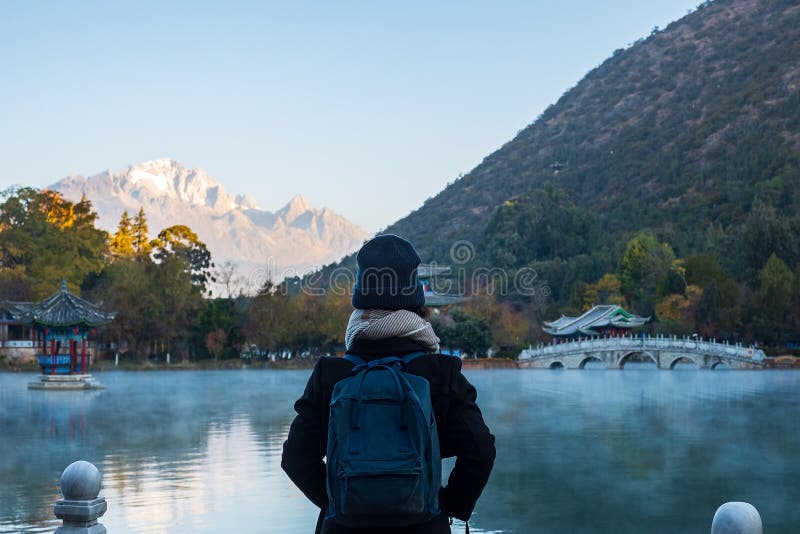 Young Woman Traveler Traveling At Black Dragon Pool With Jade Dragon Snow Mountain Background, Landmark And Popular Spot For