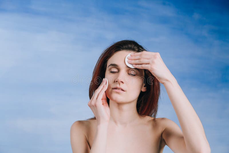 Young woman with a two sponge wihte background cotton pads cleans problem skin with closed eyes royalty free stock image Young woman with a two sponge wihte background cotton pads cleans problem skin with closed eyes royalty free stock image