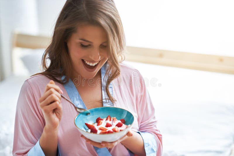 Portrait of young woman in underwear eating cereals