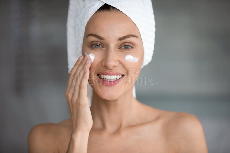 Young woman use revitalizing facial cream in bathroom