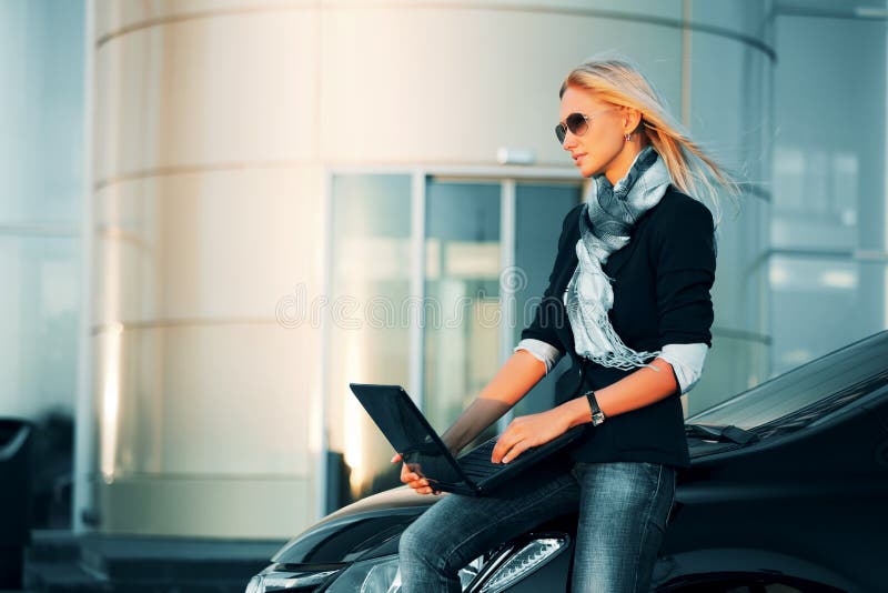 Joven moda mujer de negocios computadora portátil de acuerdo a su auto.