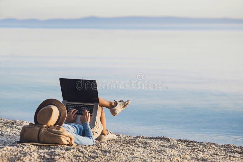 Young woman using laptop computer on a beach. Freelance work concept stock images