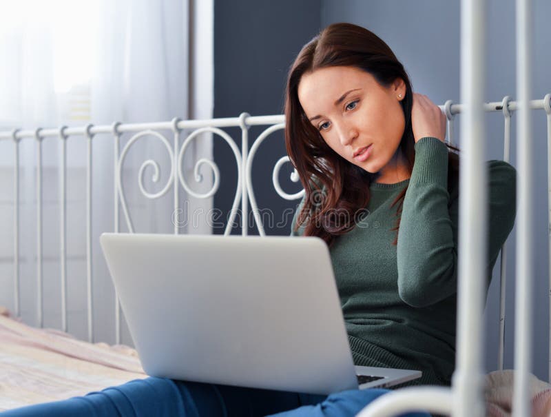 Young woman using laptop on her bed stock image