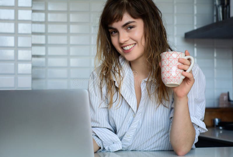 Joven una mujer café taza a su computadora portátil ordenador personal en La cocina sobre el.