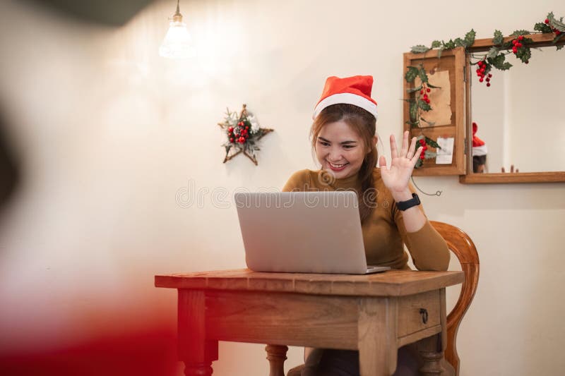 Young Woman Video Calling on Christmas Day, Wearing Santa Hat, Smiling and Waving, Celebrating Holiday Season Virtually royalty free stock photos