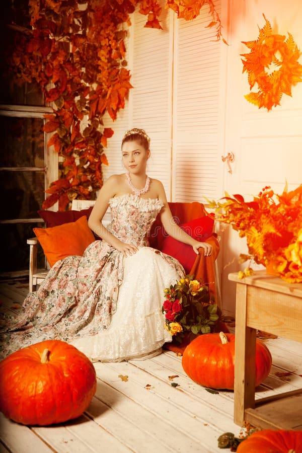 Young woman in vintage dress on autumn porch. Beauty girl in fa