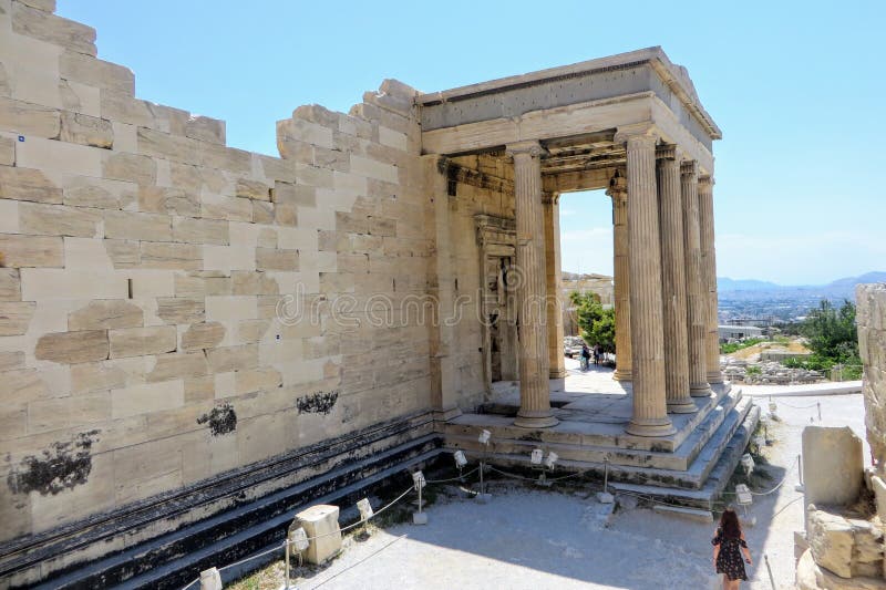 A young woman walking around the Acropolis by herself admiring the glorious ancient Greek Old Temple of Athena atop the Acropolis