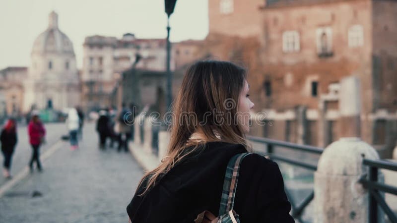 Young woman walking in city centre, Roman Forum. Female traveler takes photo of old town ruins. Girl exploring Italy.