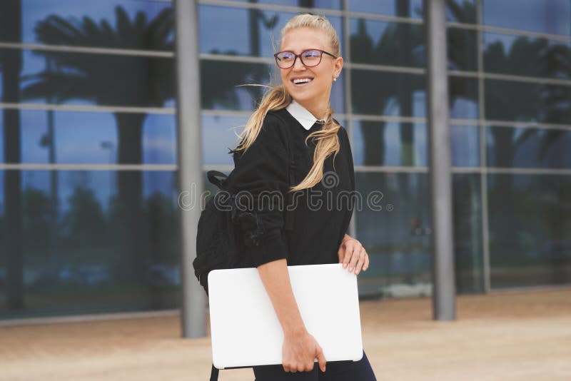 Young woman walking by the office building holding a laptop royalty free stock photography Young woman walking by the office building holding a laptop royalty free stock photography