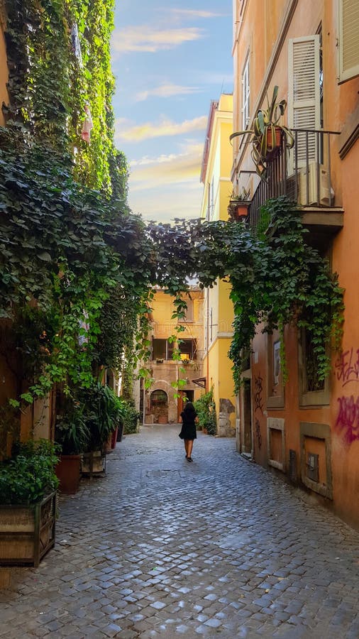 A young woman walks under an ivy and plant covered walkway on a narrow alley in the Trastevere district of Rome, Italy stock photography A young woman walks under an ivy and plant covered walkway on a narrow alley in the Trastevere district of Rome, Italy stock photography