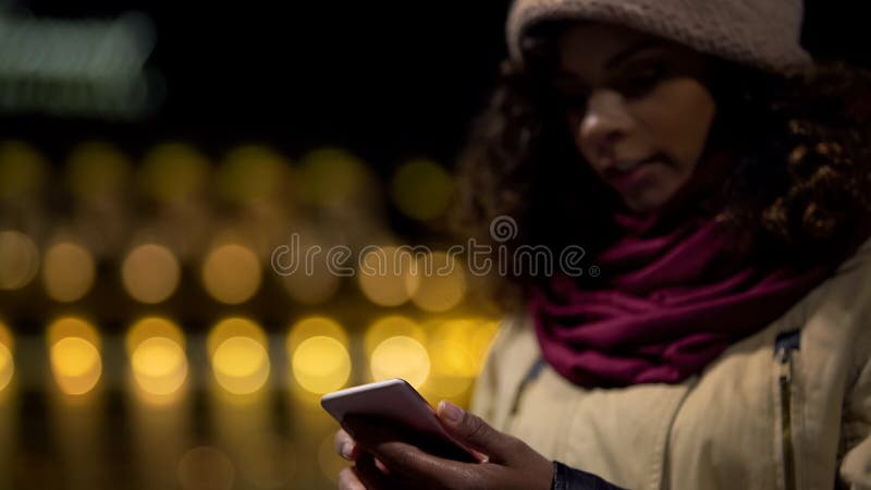 Young woman watching social media newsfeed and waiting for friends outdoors stock photography Young woman watching social media newsfeed and waiting for friends outdoors stock photography