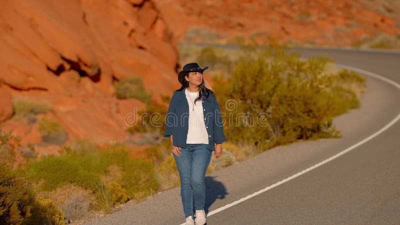 Young Woman Wearing a Cowboy Hat Walking Down a Lonesome Road in the ...