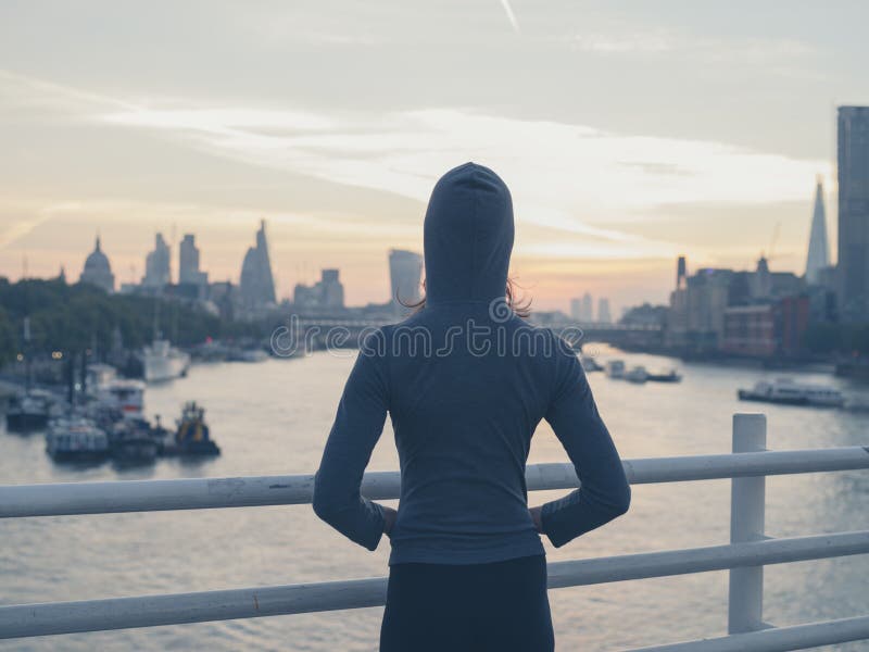 Young woman wearing hoodie on bridge in London at sunrise