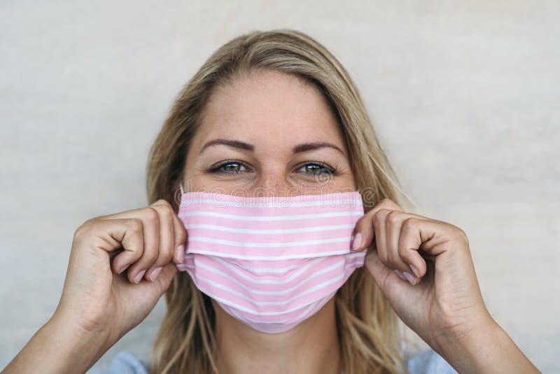 Young woman wearing pink face mask portrait - Blonde female using protective facemask for preventing spread of corona virus - Health care and pandemic crisis concept