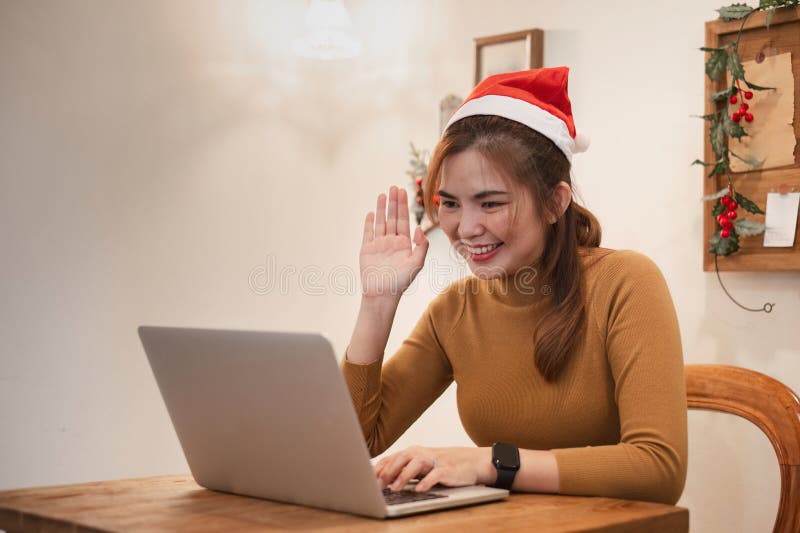 Young Woman Video Calling on Christmas Day, Wearing Santa Hat, Smiling and Waving, Celebrating Holiday Season Virtually royalty free stock photos