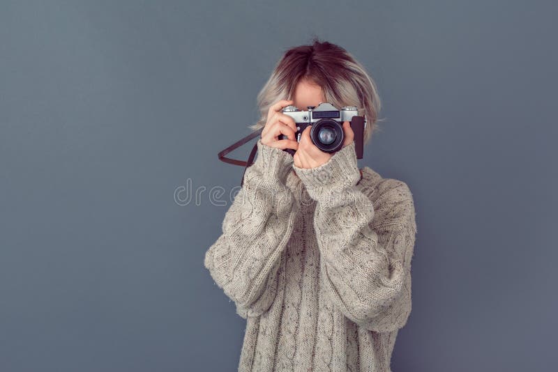 Young woman in a woolen sweater isolated on grey wall winter concept taking photos