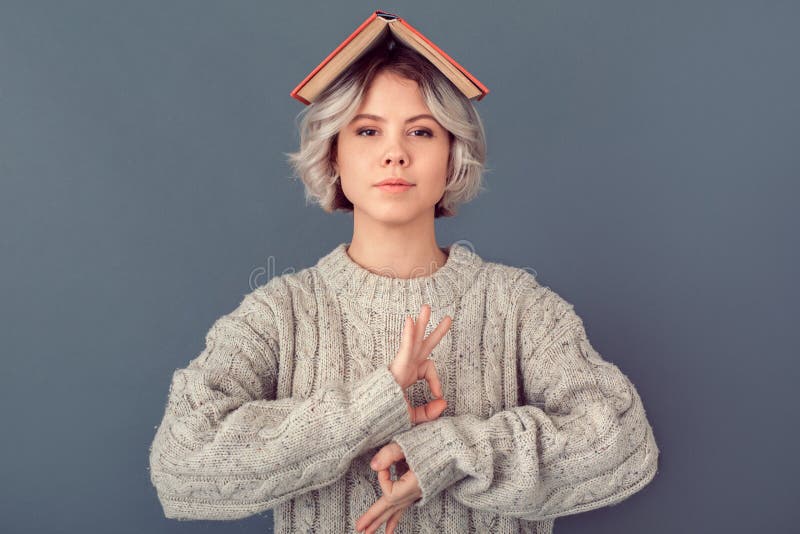 Young woman in a woolen sweater on grey wall winter concept meditating