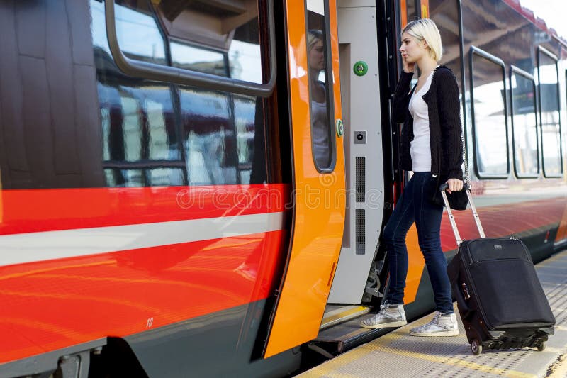 Young Woman With Wheeled Luggage Boarding Train stock photo Young Woman With Wheeled Luggage Boarding Train stock photo