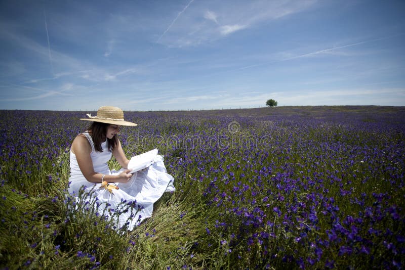 Young woman in white dress reading book outdoors