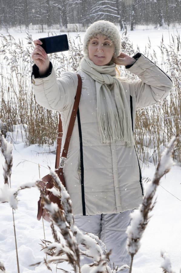 Young woman in a white jacket makes a selfie on the coast of the winter forest lake royalty free stock photos Young woman in a white jacket makes a selfie on the coast of the winter forest lake royalty free stock photos