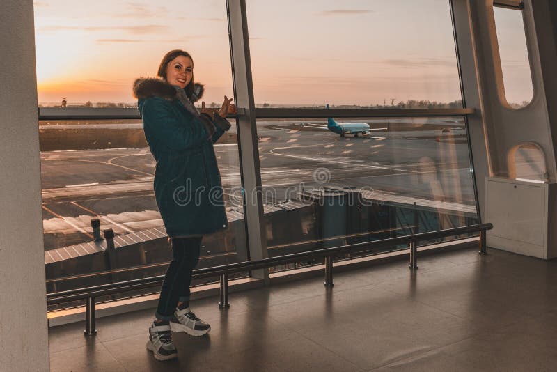 Young woman in winter clothes waiting for her flight at the airport