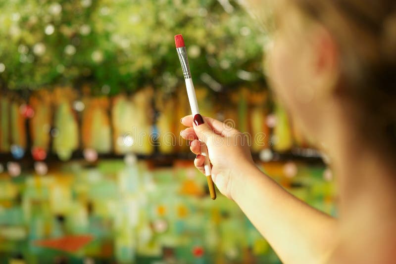 Zozadu žena ruke drží maľovanie štetcom a študovať zloženie obraz na plátno.