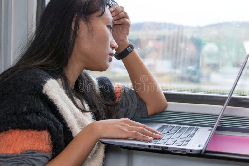 A young woman working on a computer on a train stock photo A young woman working on a computer on a train stock photo