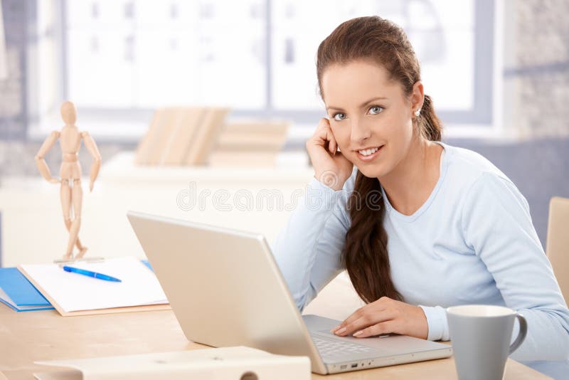 Young woman working on laptop in bright office stock photo