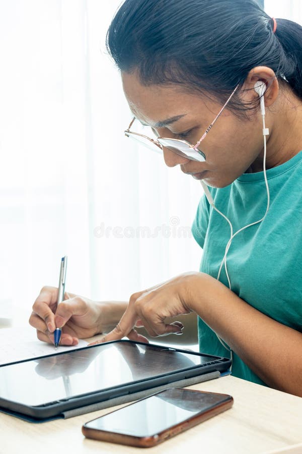 A young woman working with a tablet against the light from the window stock image