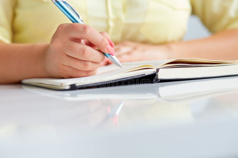 Young woman writes to black diary stock photo