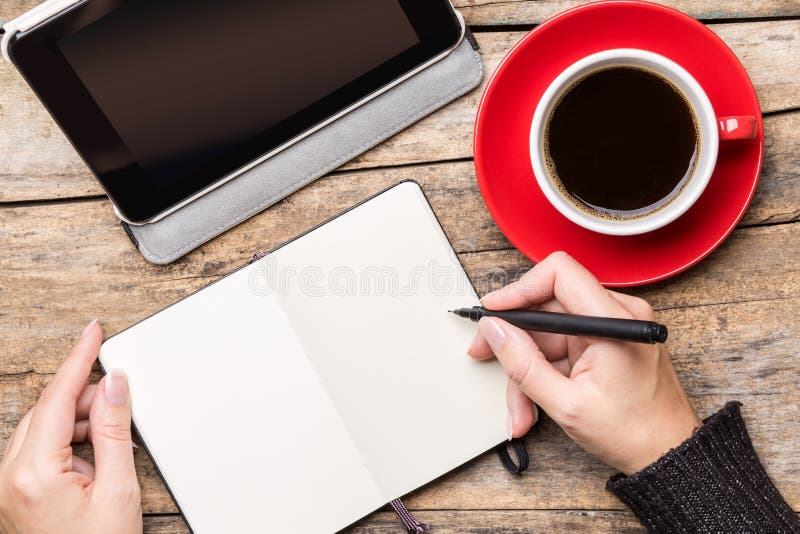Young woman writing or drawing into notepad