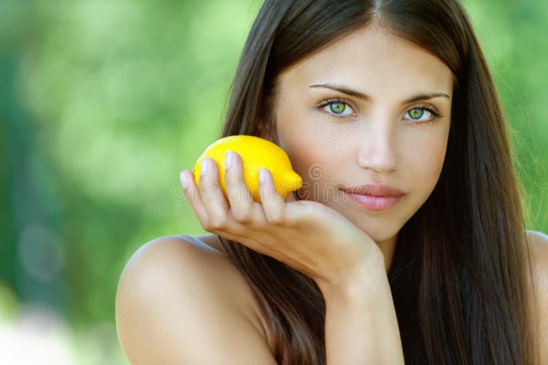 Retrato hermoso mujer joven limón, contra de verano verde.