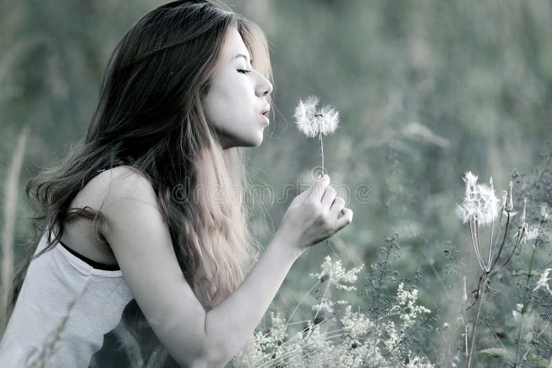 Young women blowing dandelion